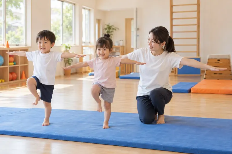 先生と一緒にマットでバランス運動に取り組む幼児